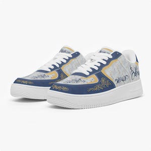 May include: Pair of white-soled sneakers with a blue and gold design. The sneakers feature a white lace-up closure and a blue and gold decorative pattern on the sides and toe. The shoes have a white sole.