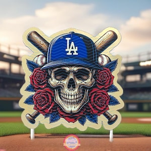 May include: A gold skull wearing a blue baseball cap with the letters "LA" on it. The skull is surrounded by red roses and two crossed baseball bats. The background is a blurred image of a baseball stadium.