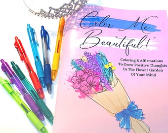 May include: A colouring book titled Color Me Beautiful! Coloring & Affirmations To Grow Positive Thoughts In The Flower Garden Of Your Mind by Jennifer Lucas Gibbs, featuring a bouquet illustration, alongside a silver tiara and six coloured pens.