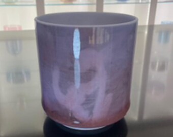May include: A cylindrical glass with a gradient color scheme, transitioning from a deep red at the base to a soft purple at the top. The glass has a smooth, polished surface and a wide opening. The interior features a wispy, cloud-like design.