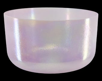 May include: A pearlescent, iridescent singing bowl with a rounded shape. The bowl has a smooth, polished surface that reflects light, creating a shimmering effect. The bowl is a soft, opalescent color, with hints of pink, blue, and green.