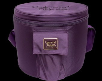 May include: A deep purple, cylindrical carrying case with a zippered top and a small front pocket. The case has a shoulder strap and the text "Crystal Tones" is visible on a gold-colored label on the front.