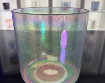 May include: A clear, iridescent glass bowl with a cylindrical shape. The bowl has a textured surface and displays a rainbow of colors, including green, purple, and yellow. The words "Crystal Tones" are printed on the bottom.