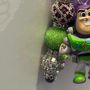 May include: A white ceramic mug with a black handle and the text "But First, Coffee" in a bold, black font. The mug is set against a blurred background, suggesting a cozy setting.