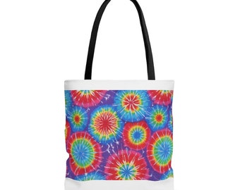 May include: A white tote bag with black handles and a colourful tie-dye pattern. The pattern features a variety of shades of blue, red, yellow, and purple.