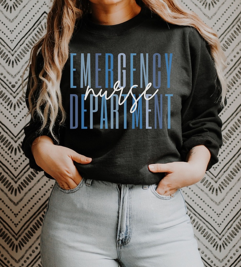 May include: Black sweatshirt with the words "EMERGENCY nurse DEPARTMENT" in blue and white lettering. The word "nurse" is in a cursive font. The sweatshirt is worn with light blue jeans.