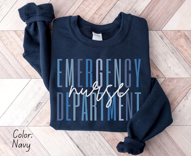 May include: Navy blue sweatshirt with the words "EMERGENCY nurse DEPARTMENT" in a gradient blue and white font. The sweatshirt is a crew neck style.