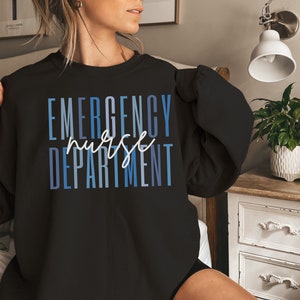 May include: Black sweatshirt with the words "EMERGENCY nurse DEPARTMENT" in blue and white lettering. The word "nurse" is in a cursive font. The sweatshirt is a crew neck style.