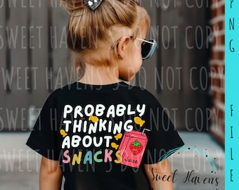 May include: A child wearing a black t-shirt with the text "Probably Thinking About Snacks" and a cartoon illustration of a juice box with a strawberry.