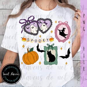 May include: White t-shirt featuring Halloween-themed graphics. Designs include ghosts in heart-shaped frames, a witch in a pink frame, a pumpkin, a black cat, bats, and the word "SPOOKY". The shirt has a round black logo that says "Sweet Haven's".