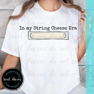 Könnte beinhalten: Weißes T-Shirt mit dem Text "In my String Cheese Era" über einer Grafik von Käsesnacks. Das Shirt hat auch ein rundes Logo mit dem Text "Sweet Havens".