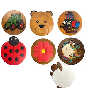 May include: Set of ten wooden coasters featuring various designs, including a tractor, a bear, a pirate ship, a ladybug, a flower, a unicorn, and a sheep. The coasters are painted in bright colours and have a rustic, handmade look.