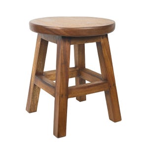 May include: A small, round wooden stool with a natural finish. The stool has a circular seat and four sturdy legs connected by a square frame. The wood grain is visible, giving it a rustic appearance. The stool is approximately 30 cm tall.