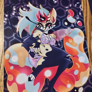 May include: A vibrant art print featuring a stylized anthropomorphic character with a fox-like face, adorned with a colorful palette of blues, reds, and oranges. The character is set against a dark background with geometric patterns and bubble-like shapes.