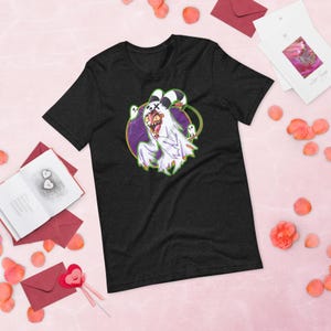 May include: A black short-sleeve t-shirt featuring a graphic print of a cartoon character dressed in a white ghost costume with a red face, sharp teeth, and black X-shaped eyes, surrounded by a purple circular background and small white ghosts.