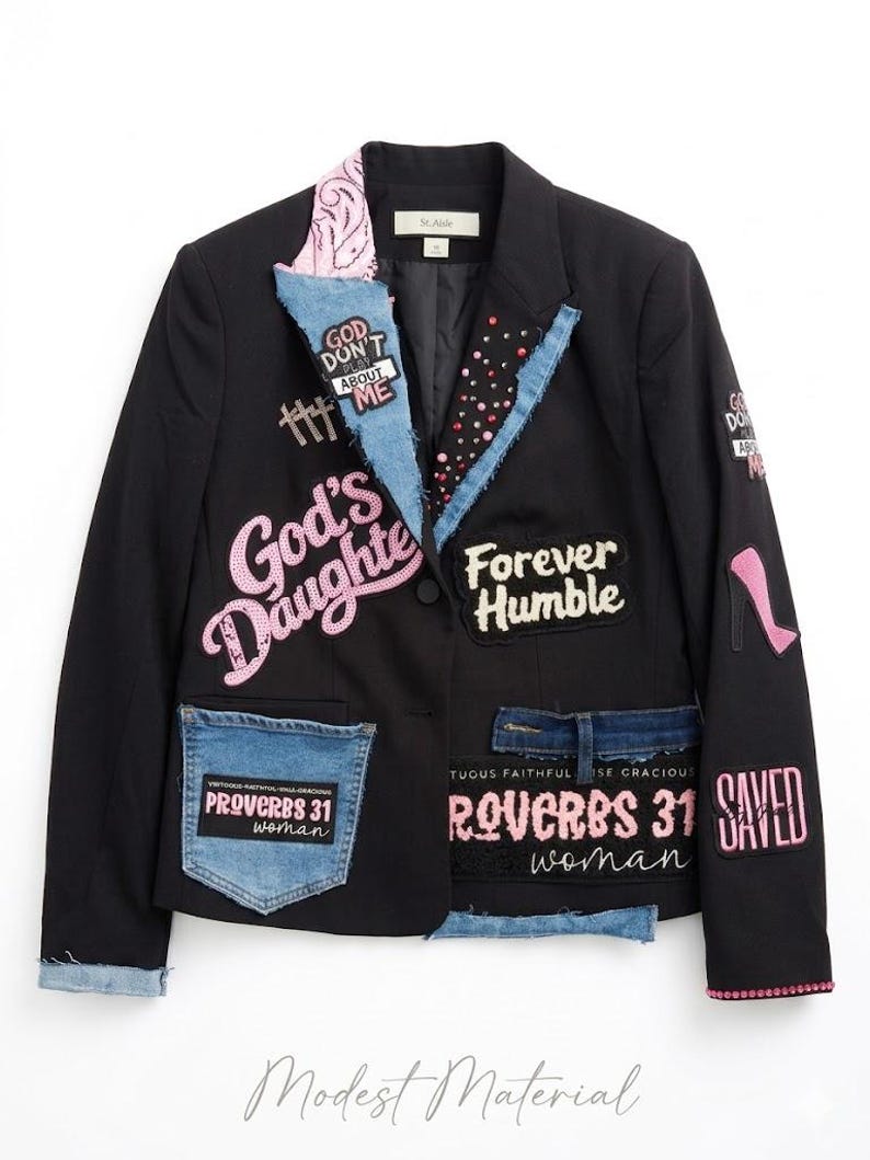Puede incluir: Blazer negro con detalles de mezclilla y parches. Adornos que incluyen texto rosa con lentejuelas que dice "God's Daughter", "Forever Humble" y "Saved". Bolsillo de mezclilla con texto "Proverbs 31 Woman". Parche de tac&oacute;n alto rosa.