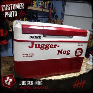 May include: A red and white chest-style cooler featuring the text DRINK Jugger-Nog, That's a cold one!, Made with real eggs!, and a 10 cent price graphic. The cooler has a rectangular lid, a smooth finish, and a ventilation grate on the side.