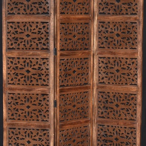 May include: A three-panel room divider made of dark brown wood with intricate carved floral designs. Each panel has five sections with a different design.