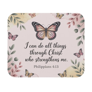 May include: A square, light pink decorative item with a butterfly and floral design. The text "I can do all things through Christ who strengthens me. Philippians 4:13" is written in black script. Butterflies and leaves surround the text.