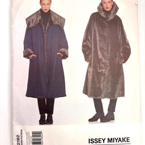 May include: A pattern for two long coats. One coat is navy blue with a faux fur collar and cuffs. The other coat is brown with a large collar. The pattern is labeled "ISSEY MIYAKE VOGUE DESIGNER ORIGINAL".