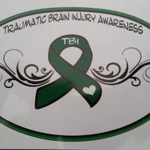 Könnte beinhalten: Grünes Band mit den Buchstaben TBI in der Mitte, umgeben von schwarzen floralen Designs. Das Band befindet sich auf einem weißen ovalen Hintergrund mit dem Text "Traumatic Brain Injury Awareness" am oberen Rand.