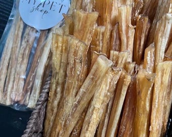 May include: A close-up shot of a basket filled with light brown, dried pet treats. Some treats are in a clear plastic bag with a sticker that reads "MY PET shop". The treats have a textured appearance.