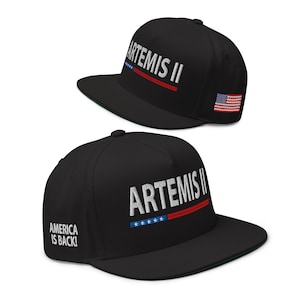 May include: Two black baseball caps with the text "ARTEMIS II" embroidered in white. One cap has a small American flag on the side. The other cap has the text "AMERICA IS BACK!" on the side.