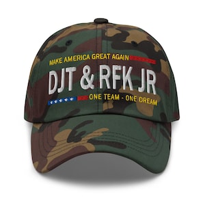 May include: Camouflage baseball cap with the text "Make America Great Again" in red and white, "DJT & RFK JR" in white, and "One Team - One Dream" in yellow. The cap has a red, white, and blue American flag embroidered on the front.