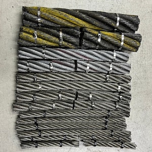 May include: A stack of coiled steel cables with black and yellow striped insulation and silver metal clamps.