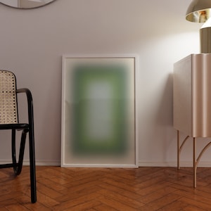 Puede incluir: Una impresión de arte abstracto enmarcada en blanco con un degradado de verde y azul. La impresión está colgada en una pared blanca sobre un suelo de madera.