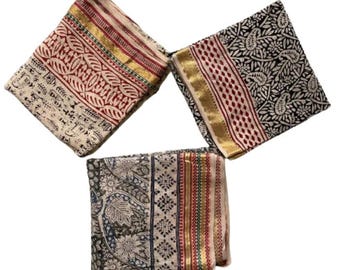 May include: Three white cotton scarves with different patterns and colorful borders. The scarves have a paisley design, a floral design, and a geometric design.