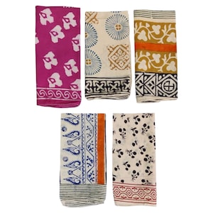 May include: Five folded fabric napkins with various patterns. One is fuchsia with white floral shapes, another is cream with blue circles and brown squares, and a third is yellow with orange and black designs. The other two are cream with black floral and blue patterns.