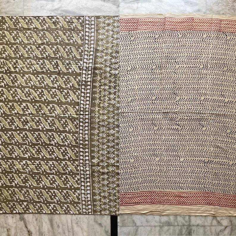 May include: Two fabric panels with different patterns. One panel is olive green with a white and light green repeating design. The other panel is off-white with a black wavy pattern and a red border. The fabric is likely cotton or linen.