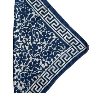 May include: A blue bandana with a white floral pattern and a white Greek key border.