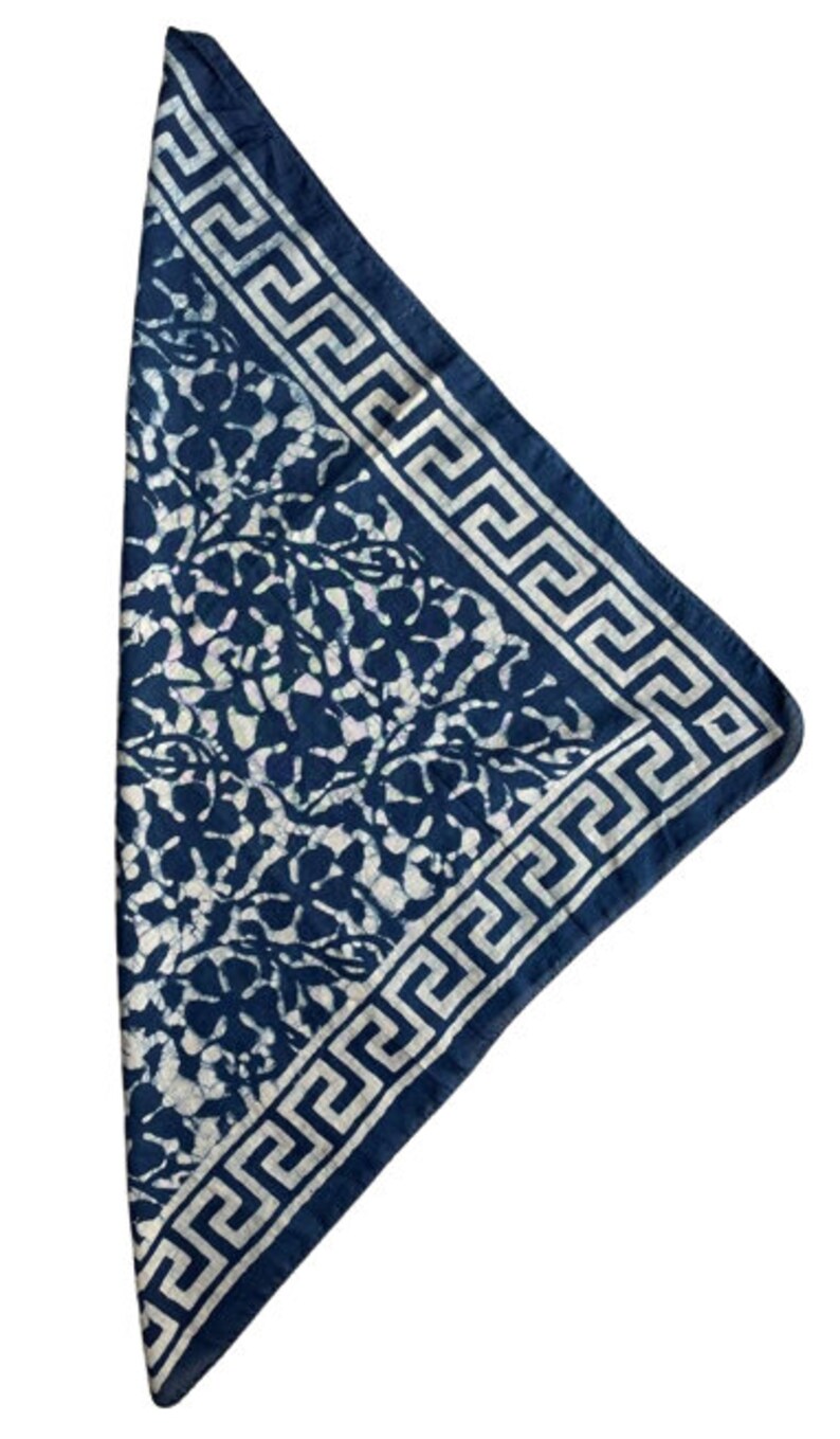 May include: A blue bandana with a white floral pattern and a white Greek key border.