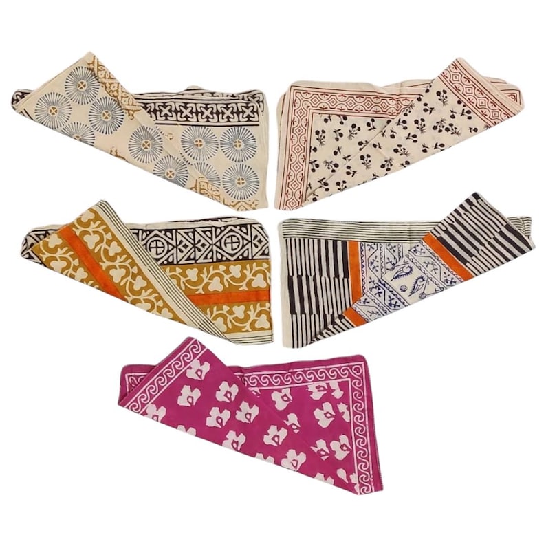 May include: Five folded cotton bandanas with various patterns. The bandanas feature designs in cream, orange, black, and pink. The patterns include floral, geometric, and striped motifs. The bandanas are arranged in a fan shape.