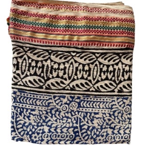 May include: A cream-coloured cotton fabric with a blue and black floral print. The fabric has a gold, red and green striped border.