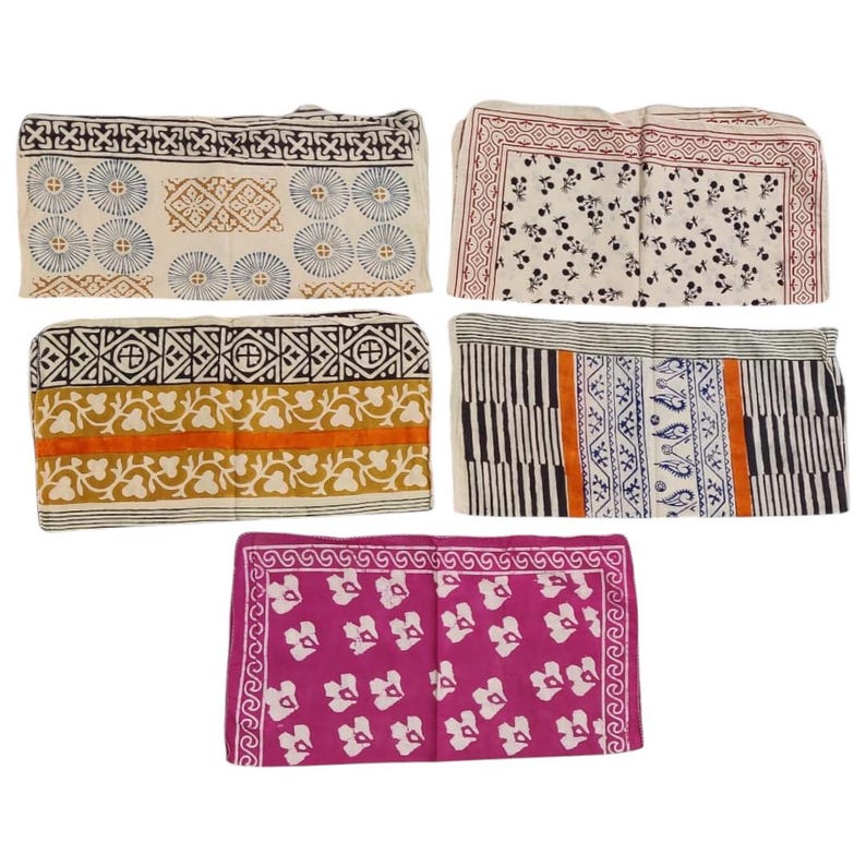 May include: Five folded fabric items with various block print designs. The patterns include floral, geometric, and abstract motifs in colors like blue, brown, orange, and pink. The fabrics appear to be cotton or a similar material, suitable for home decor or crafting.