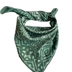 May include: A green bandana with a white geometric pattern. The bandana is folded and tied in a knot.