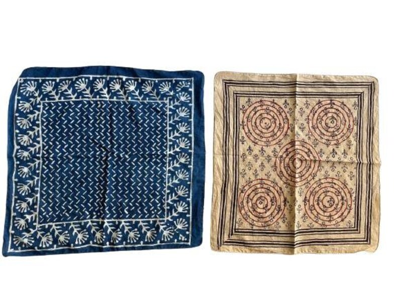 May include: Two square cotton bandanas with different patterns. The first bandana is dark blue with a white floral pattern. The second bandana is beige with a brown and pink geometric pattern.