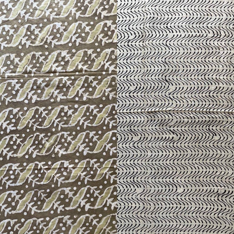 May include: A textile with two distinct patterns. One side features a repeating design of white leaves and dots on a brown background. The other side has black wavy lines on a cream background. The fabric appears to be cotton or linen.