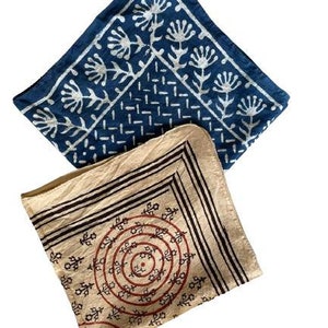 May include: Two cotton bandanas, one blue with a white floral pattern and the other beige with a brown and red circular pattern.