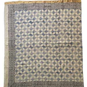 May include: A white cotton fabric with a blue and white geometric pattern. The fabric has a gold border.