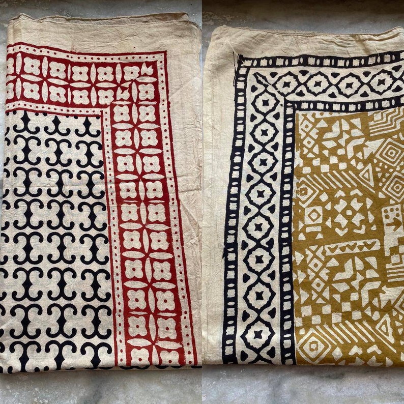 May include: Two cotton fabric squares with different block printed designs. One square has a black and white geometric pattern with a red border. The other square has a black and white geometric pattern with a gold border.