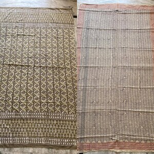 May include: Two patterned textiles. One is olive green with a repeating white and olive design. The other is off-white with a repeating black and off-white design. Both have decorative borders.