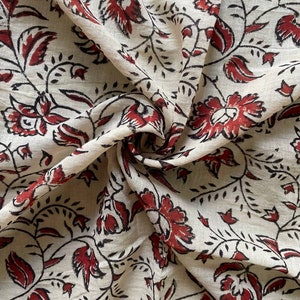 May include: A white fabric with a red and black floral print. The fabric is folded and shows the pattern on both sides.