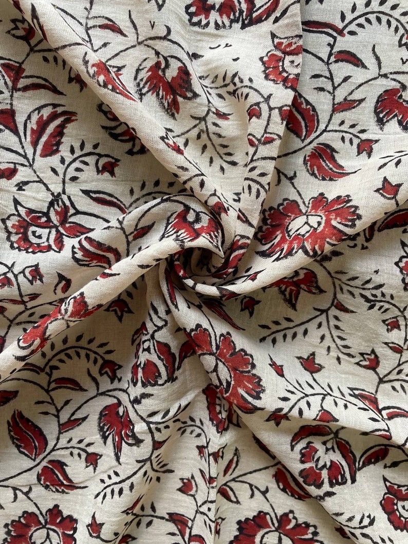 May include: A white fabric with a red and black floral print. The fabric is folded and shows the pattern on both sides.