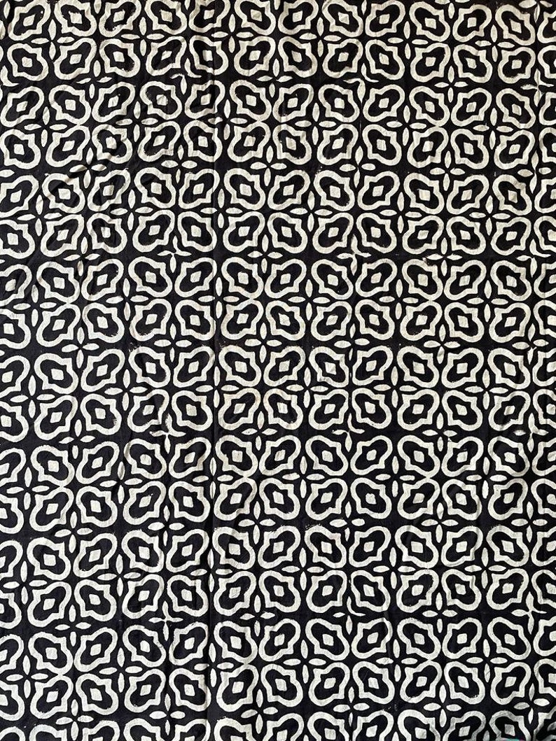 May include: Black and white fabric with a repeating pattern of stylized floral shapes.