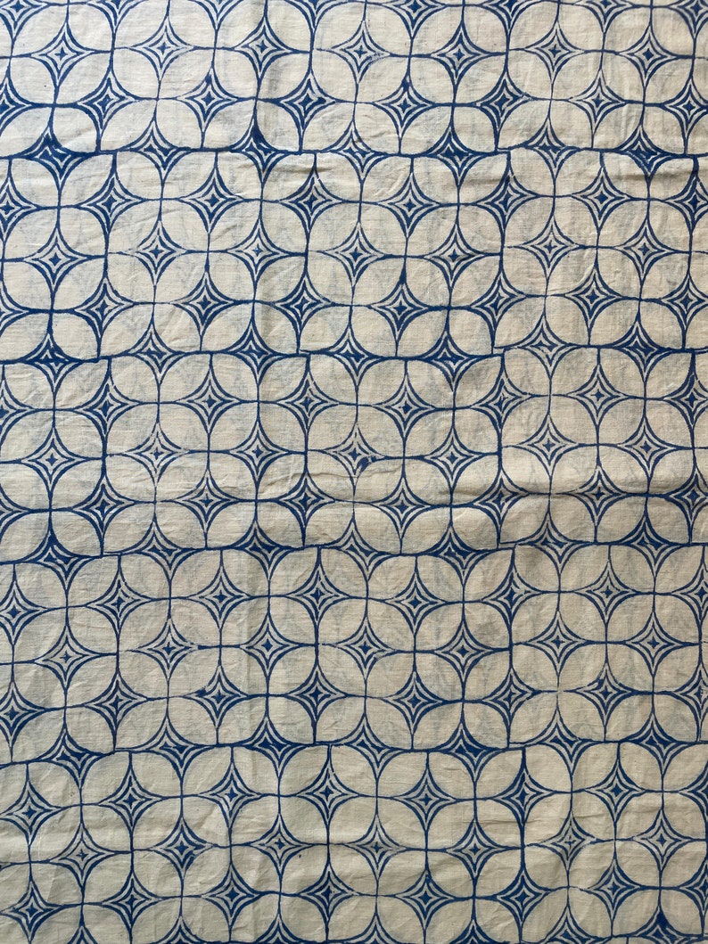 May include: A white fabric with a repeating blue geometric pattern. The pattern is made up of overlapping circles and stars.