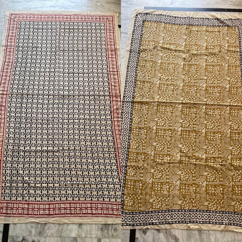May include: Two fabric squares with different patterns. The square on the left has a black and white geometric pattern with a red and white border. The square on the right has a brown and white geometric pattern with a black and white border.